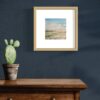 A framed watercolor painting by Lindsey Kiser of an oasis in the desert.