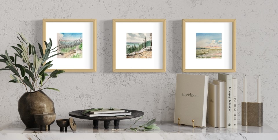 two watercolor paintings of the Rocky Mountains by Lindsey Kiser shown framed on a wall